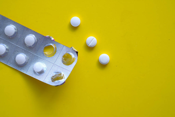 close up of white pills on yellow background  - Foto, afbeelding