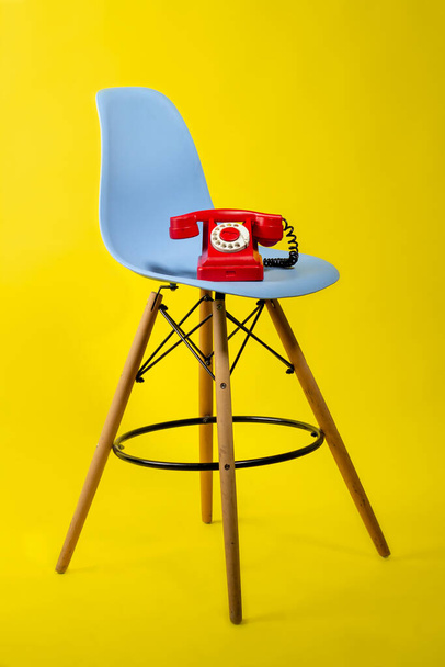 retro piros telefon egy kék szék sárga háttér 80-90-es évek - Fotó, kép