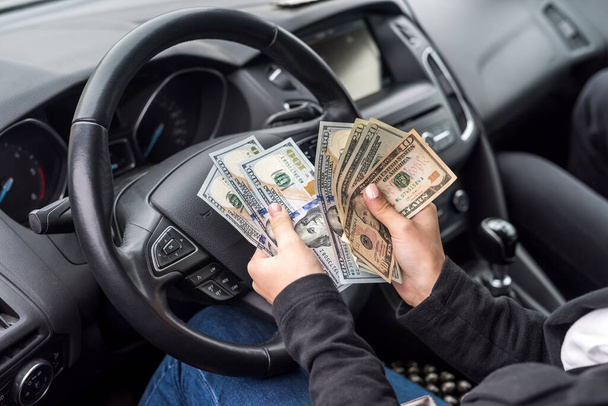 Manos femeninas con billetes de dólar primer plano en el volante
 - Foto, imagen