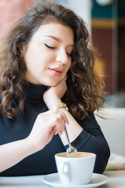 portrait of a beautiful girl in a cafe drinks coffee - Foto, afbeelding