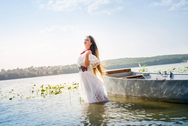 Όμορφο κορίτσι με εθνικά ρούχα στέκεται στη λίμνη - Φωτογραφία, εικόνα