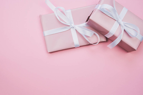 ピンクに包まれた2つのプレゼントがピンクの背景に横たわっています - 写真・画像