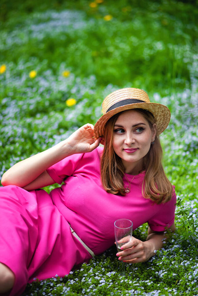 meisje op een picknick in een bloeiende zonnige tuin drinken champagne - Foto, afbeelding