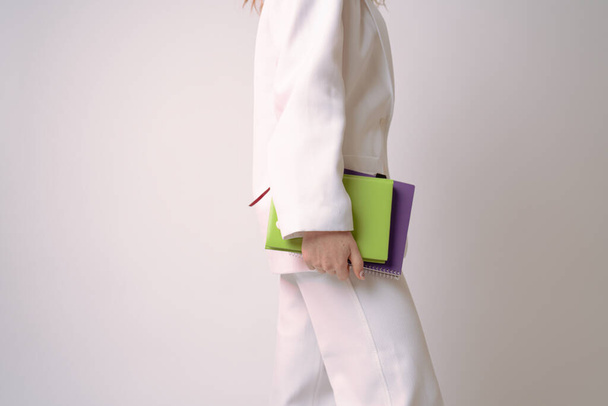 Side view fénykép elegáns nő fehér ruhában tartja zöld notebook a kezében elszigetelt szürke háttér - Fotó, kép
