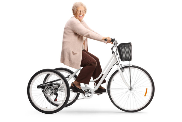 Старша жінка їде на триколісному велосипеді і сміється ізольовано на білому тлі
 - Фото, зображення