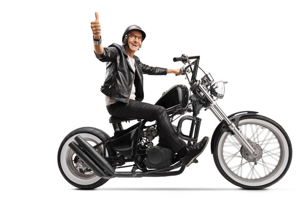 Cool mature biker in leather clothes riding a chopper and showing thumb up isolated on white background - Fotó, kép