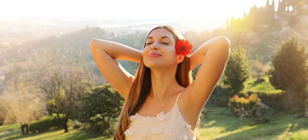 Tavaszi lány pihentető természet panoráma banner. Fiatal nő virág a fül légzés élvezi a friss levegő szabadtéri szabadidő. - Fotó, kép