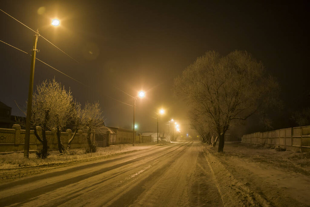 Winter im Dorf. Nachtaufnahme einer Straße mit Laternen - Foto, Bild