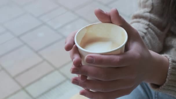 vrouwelijke handen houden papieren beker met koffie vast. meisje houdt mok, close-up, geen gezicht - Video