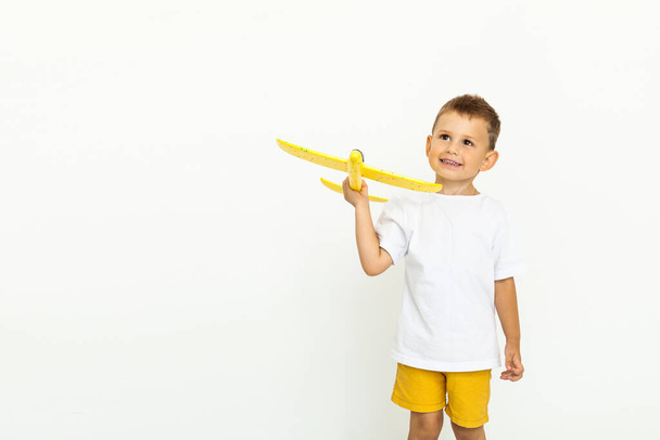 Happy cute child toddler playing with yellow toy airplane and dreaming of becoming a pilot - Fotó, kép