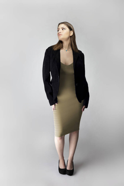 Female model posing as a sexy business woman looking confident like a boss or a manager. Her outfit is a trendy brown or tan dress with a business suit or jacket.  - Photo, Image