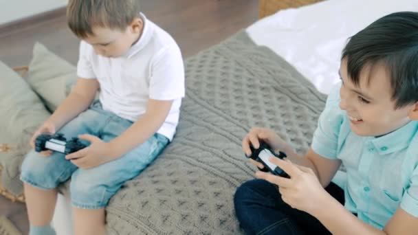 Two friends or brothers smiling and having fun playing a video game with controllers - Materiał filmowy, wideo