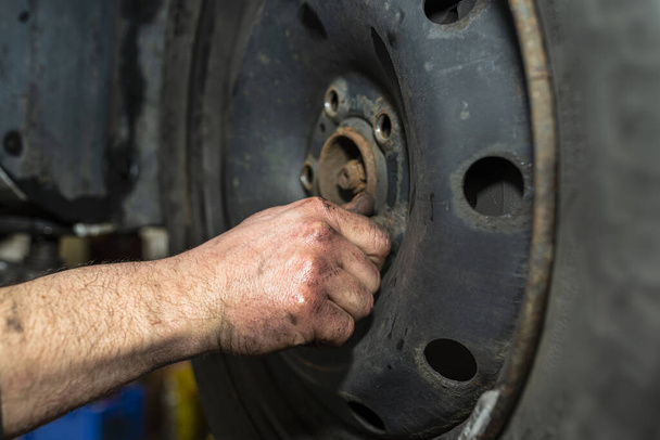 Az autószerelő behelyezi a csavarokat rögzítő acél kerék az autó használata előtt a pneumatikus csavarkulcs. - Fotó, kép