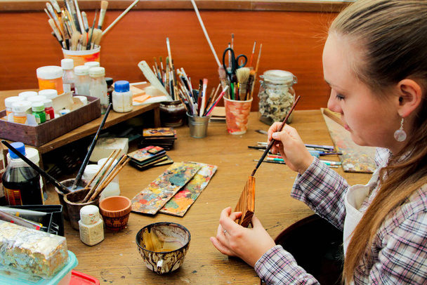 木の絵の高齢化のプロセス、木材の処理、木の汚れとトーニング。女の子のアーティストは、スタジオで絵を描く..ブラシと背景にペイント. - 写真・画像