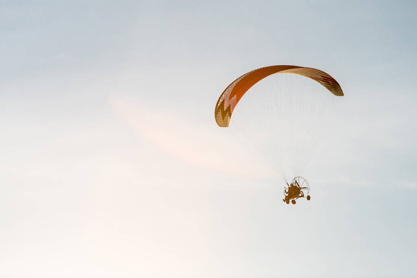 helder paraglider met een motor vliegt in de blauwe zonnige hemel - Foto, afbeelding