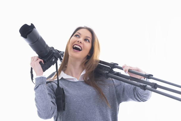 Woman holding a camera and carrying a tripod - 写真・画像