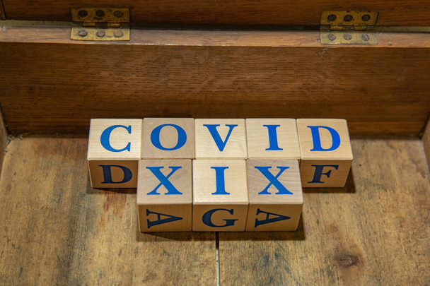 Dřevěné kostky se slovem COVID-19 ve staré hnědé krabici - Fotografie, Obrázek
