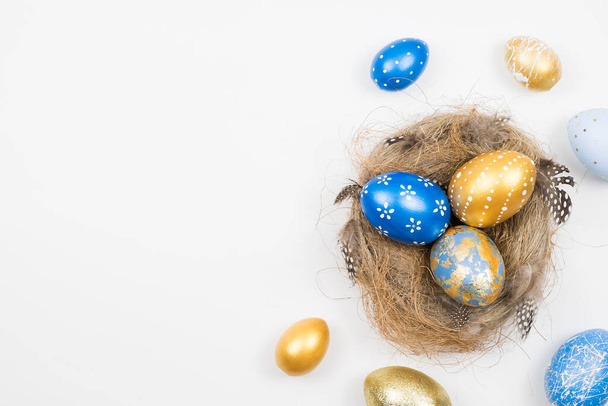 Easter golden decorated eggs in nest isolated on white background for web banner. Minimal easter concept. Happy Easter card with copy space for text. Top view, flatlay. - Fotografie, Obrázek
