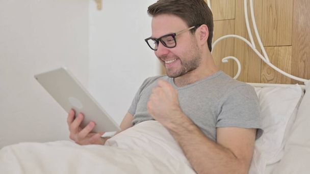 Young Man Celebrating Success on Tablet in Bed - Φωτογραφία, εικόνα