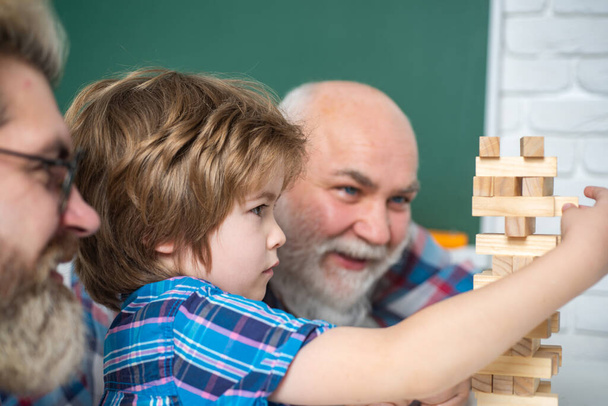 Grandfather teaching grandson how to play Jenga games. Grandfather father and son having fun together. Man family Playing Jenga. - Foto, afbeelding