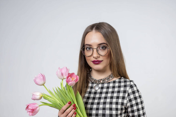 Young beautiful girl with pink tulips in her hands. - Foto, afbeelding
