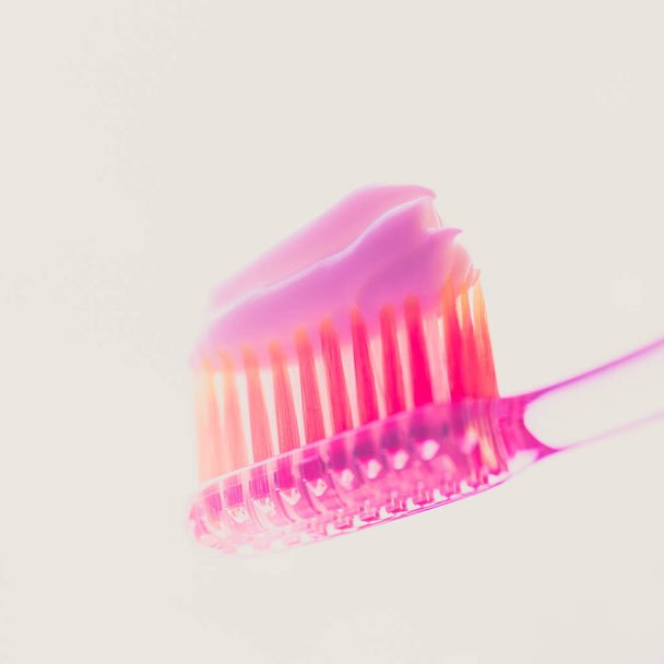 Розовая пластиковая зубная щетка с клубничной зубной пастой на изолированном фоне. Вид сбоку
 - Фото, изображение