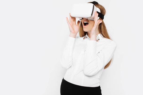 Image of a young pregnant businesswoman wearing virtual reality glasses, entertainment in the workplace, on a white background - 写真・画像