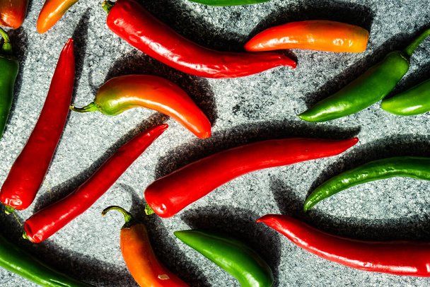 Trendy vegetable frame with ripe hot chilli peppers on stone background with deep shadows on stone background with copy space - Fotoğraf, Görsel