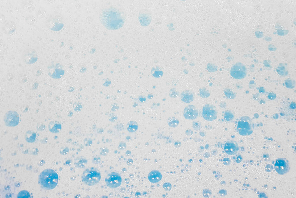 Λευκός αφρός με φυσαλίδες που ξεπροβάλλουν σε μπλε νερό - Φωτογραφία, εικόνα