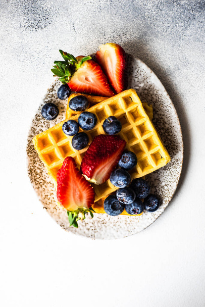Petit déjeuner européen traditionnel avec gaufres, fraises et bleuets bio sur fond de pierre avec espace de copie
 - Photo, image