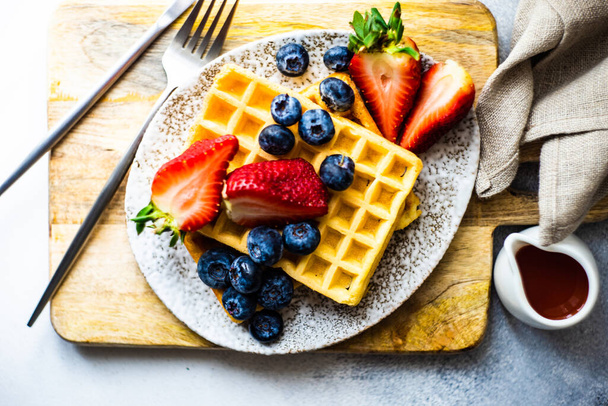 Traditional european breakfast with waffles, organic strawberry and blueberry on stone background with copy space - Fotoğraf, Görsel