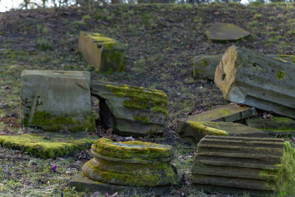 old destroyed columns overgrown with moss in the park on a sunny day in early spring - Photo, Image