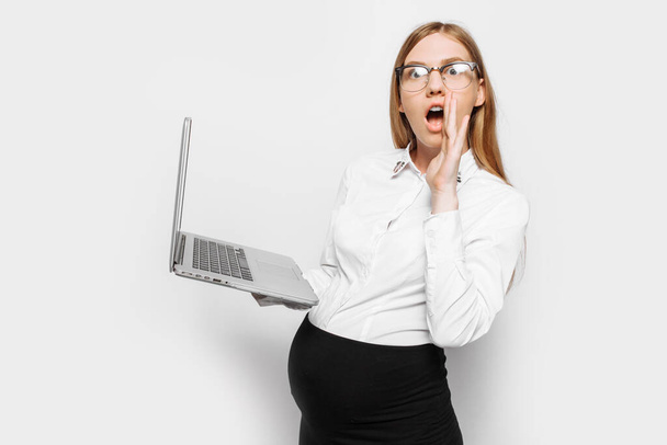 Image of young pregnant businesswoman in glasses shocked girl posing with laptop, on white background - Zdjęcie, obraz