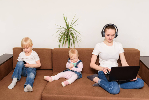άλφα παιδιά γενιάς κάθονται στον καναπέ εθισμένοι με σύγχρονα gadgets. υπερβολική χρήση συσκευών . - Φωτογραφία, εικόνα