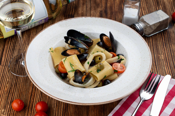 Пачері з морепродуктів макарони з гребінцями, мідіями, оливками та помідорами як ідеальна гастрономічна страва
 - Фото, зображення