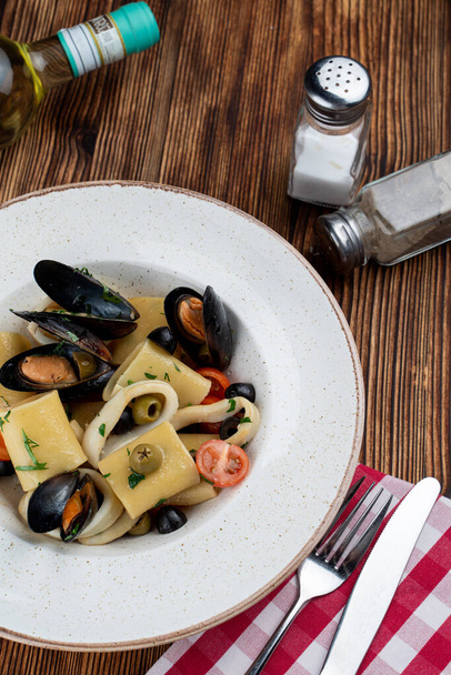 Paccheri seafood pasta with scallops, mussels, olives and tomatoes as a perfect gourmet meal - Photo, Image