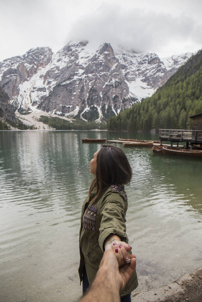Kochająca się para na Lago di Braies, imponujące zielone jezioro, które odzwierciedla wysokie zaśnieżone góry, otoczone obfitą roślinnością - Zdjęcie, obraz