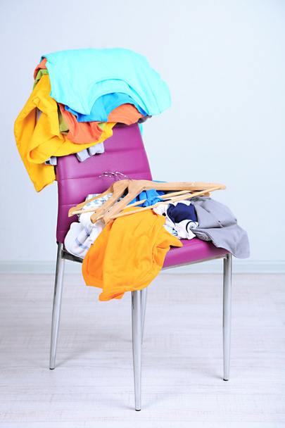 Heap of clothes on color chair, on gray background - Fotografie, Obrázek