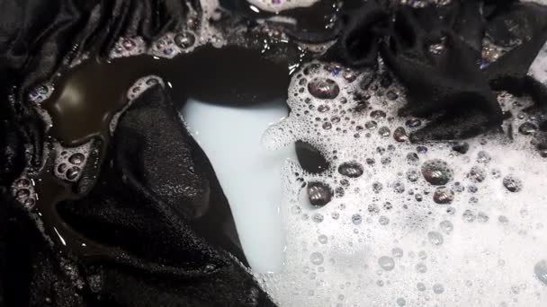 Das dunkle Ding mit Schaum im Wasser waschen und Blasen platzen. - Filmmaterial, Video