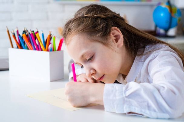 Happy cheerful child girl drawing. Creativity concept. Cute child drawing using felt-tip pen while sitting at table. - Photo, Image
