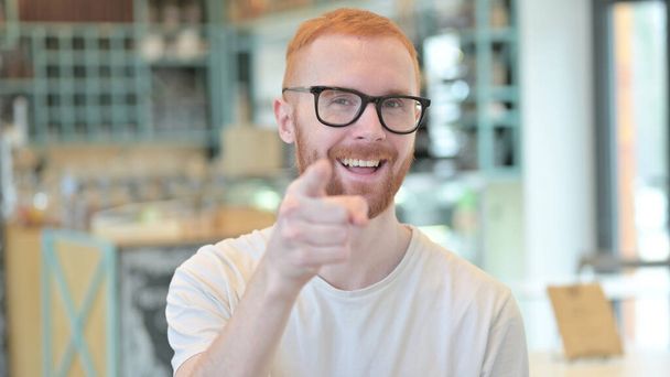Portrait of Attractive Redhead Man Pointing with Finger - 写真・画像