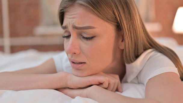 Droevige jonge vrouw huilen in bed - Foto, afbeelding