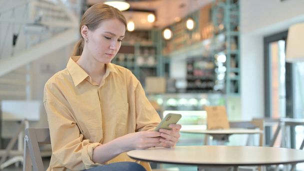Poważna młoda kobieta za pomocą smartfona w Cafe - Zdjęcie, obraz