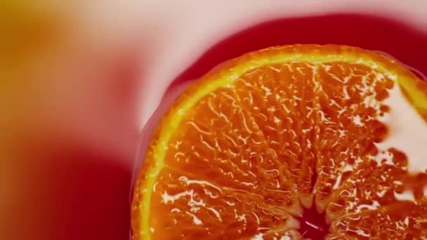 Slice of orange rotating close-up on red background - Záběry, video