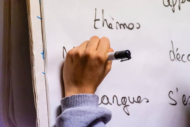 Plan rapproché d'une jeune gauchère méconnaissable écrivant des associations de mots sur un tableau à feuilles mobiles en français
 - Photo, image