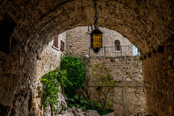 Uma passagem em túnel de uma antiga cidade medieval com uma lanterna de metal astuto pendurado no meio (Eze cidade velha, Cote d 'Azur, França
) - Foto, Imagem