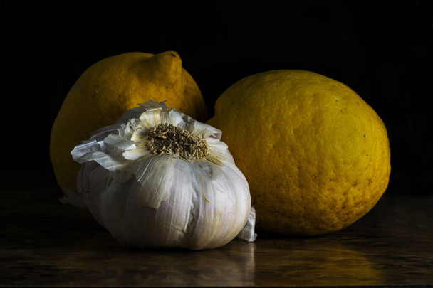 Algunos limones y un ajo en una mesa con un fondo negro
 - Foto, imagen