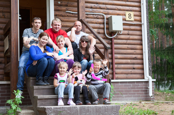 Big Caucasian family with three men, four women and three children sitting on the house porch - Φωτογραφία, εικόνα
