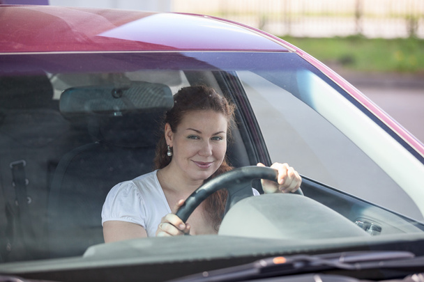 Smiling woman holding steering wheel and looking through the windscreen - Photo, image