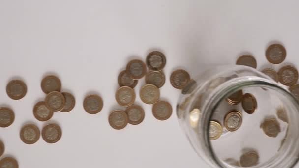 Moneda mexicana y una botella de vidrio sobre fondo blanco
 - Metraje, vídeo